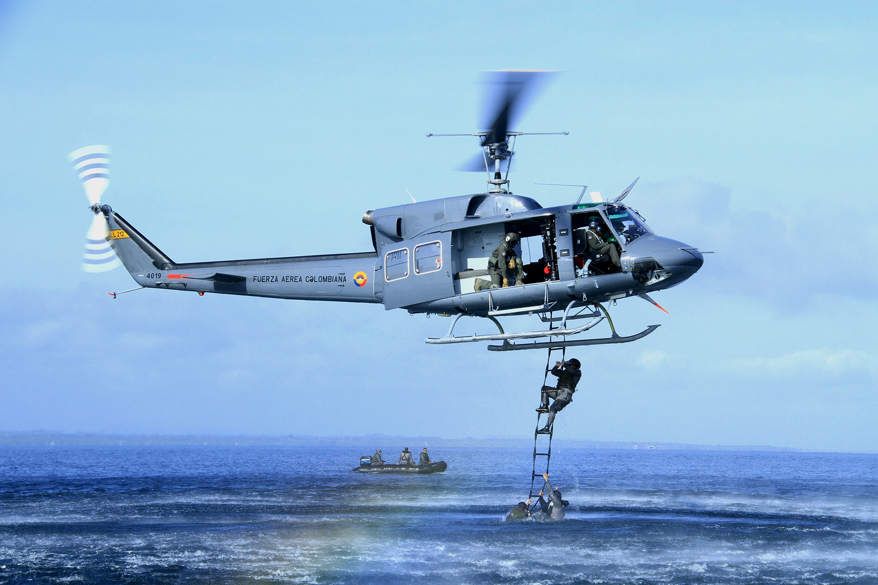 Comandos Especiales Aéreos de la Fuerza Aérea Colombiana en entrenamiento de recuperación de personal en aguas abiertas por medio de escalera textil, desplegada desde un helicóptero Bell 212.